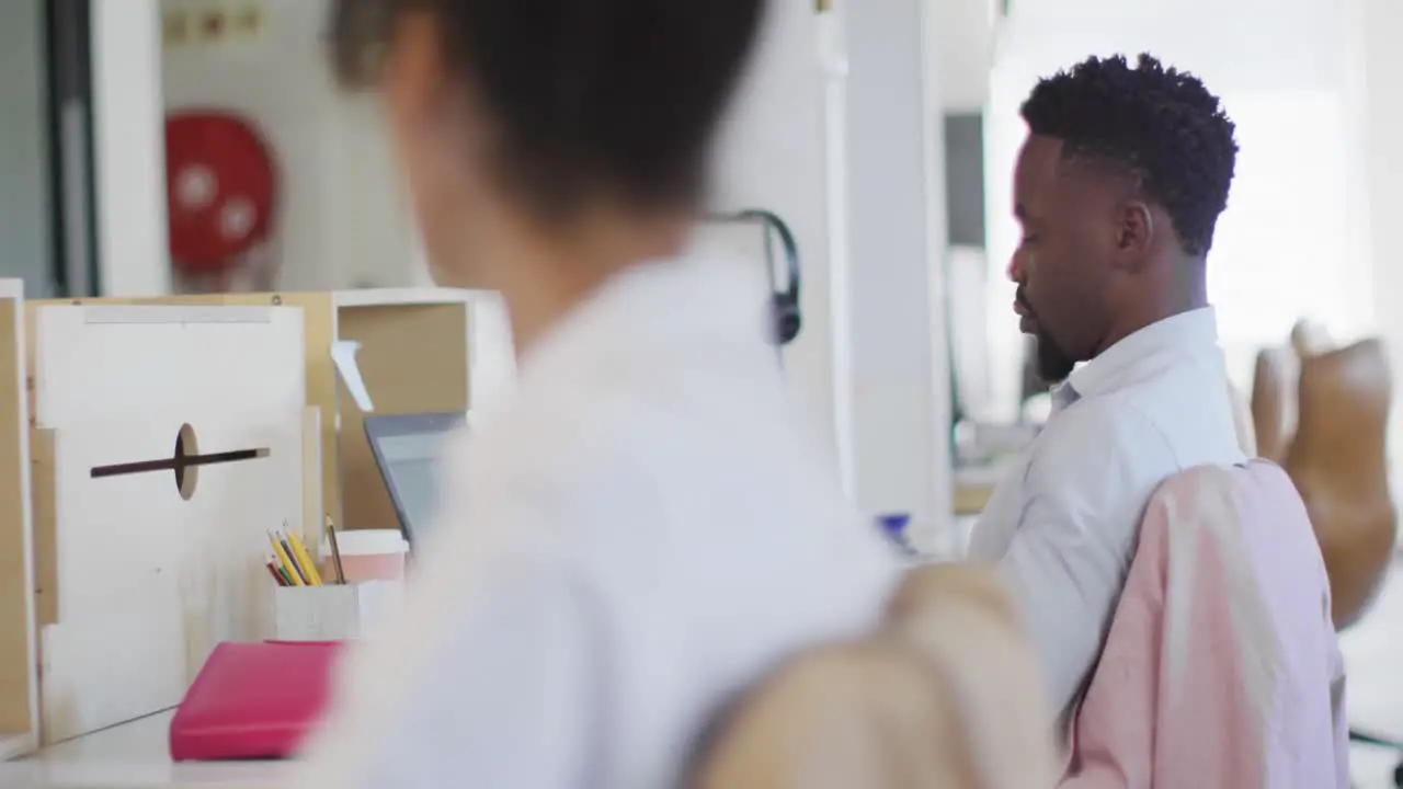 Happy african american businessman talking with colleague in creative office