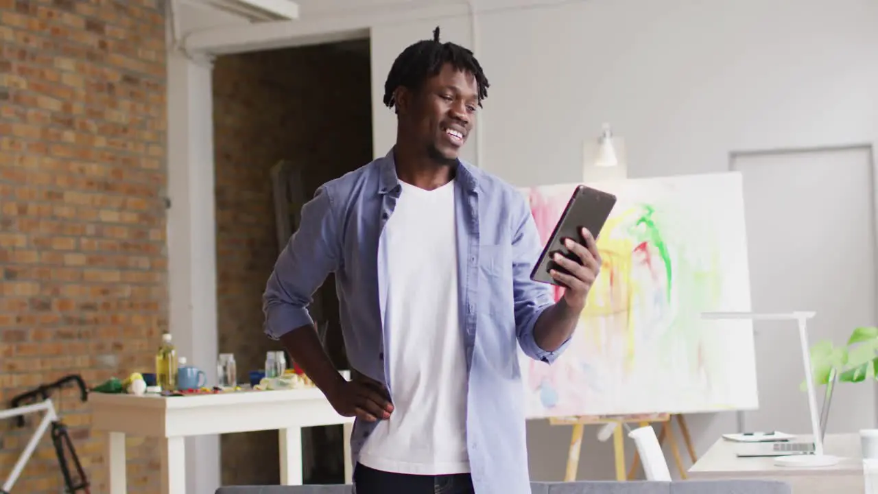 African american male artist smiling while having a video call on digital tablet at art studio