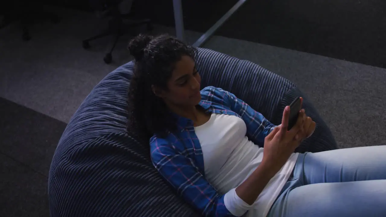 Mixed race woman lying on bean bag taking selfie and smiling