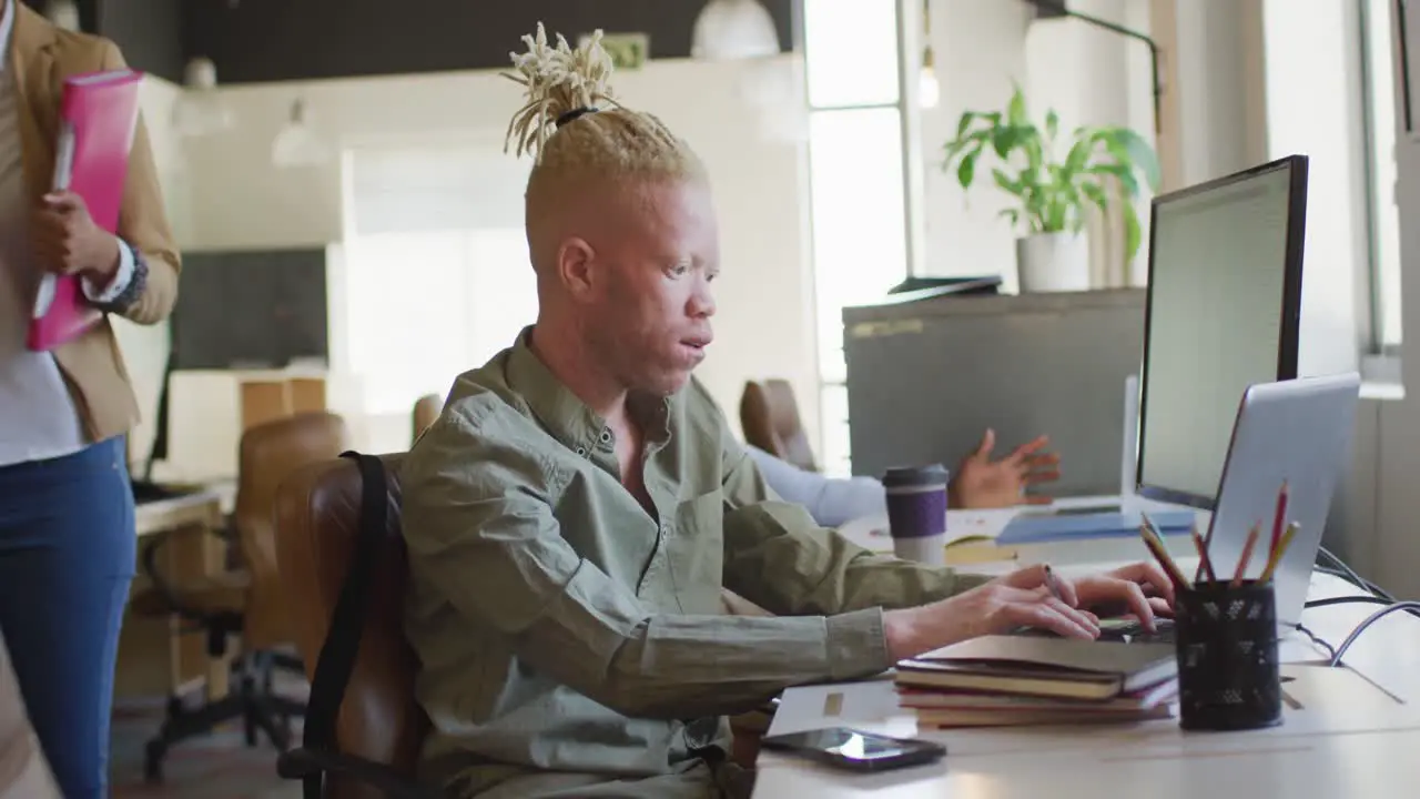 Albino african american businessman using laptop in creative office