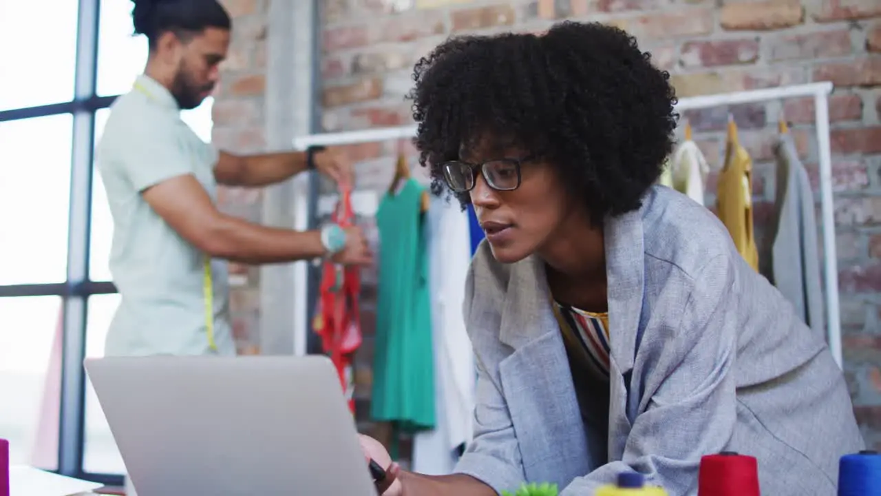 Diverse male and female fashion designers using laptop and talking on smartphone