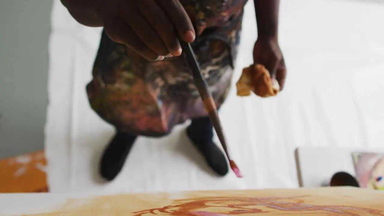 Overhead view of mid section of african american male artist painting on canvas at art studio