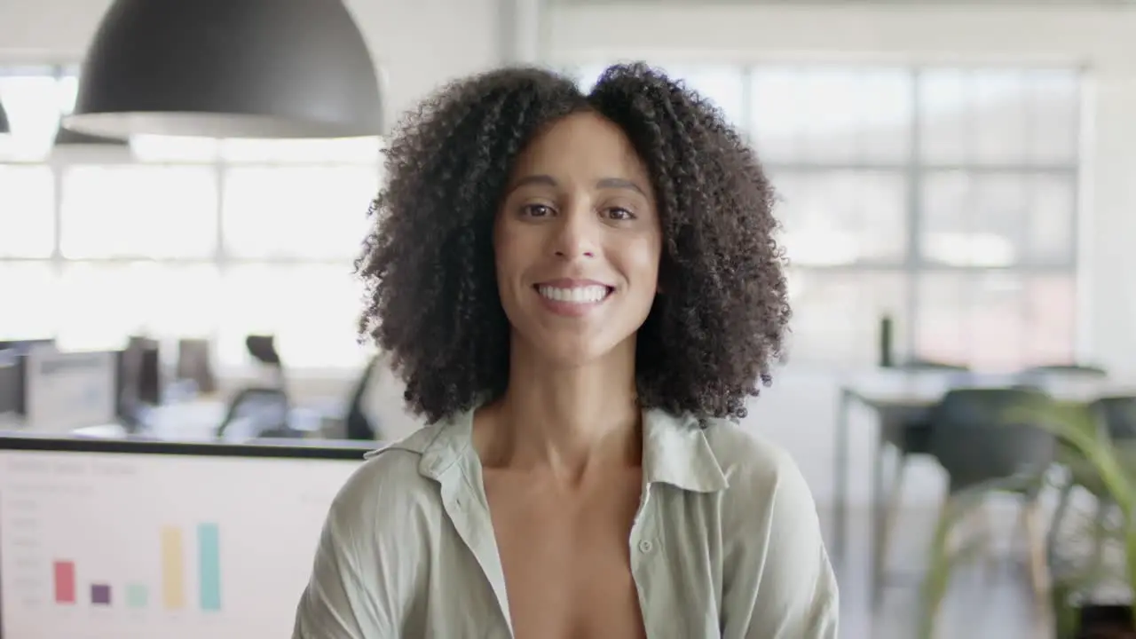 Portrait of happy biracial casual businesswoman in creative office in slow motion