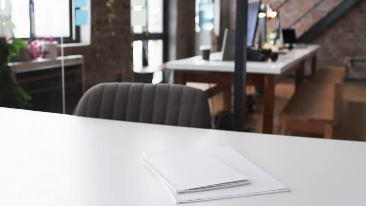 A white desk with a closed laptop and papers in a modern business office with copy space