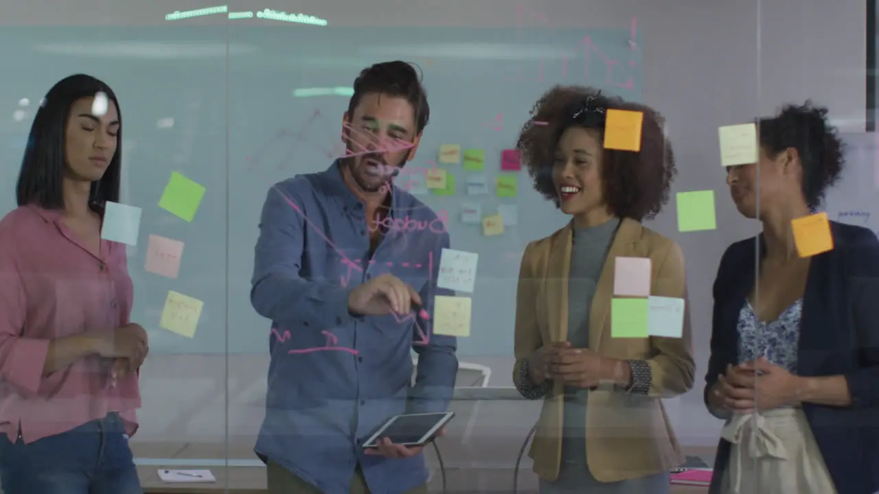 Diverse colleagues using memo notes and drawing on glass wall having a discussion