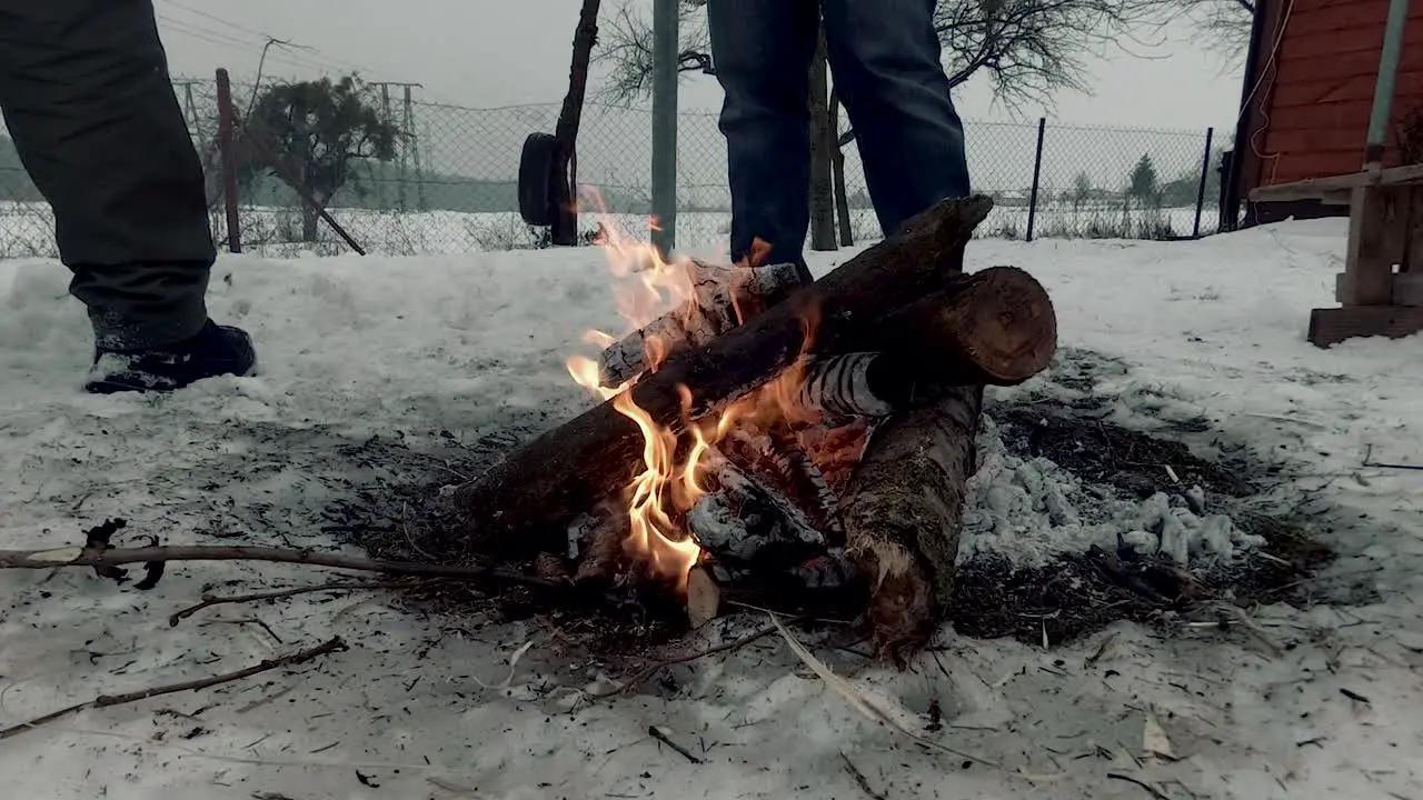 A bonfire in winter near the house with two men