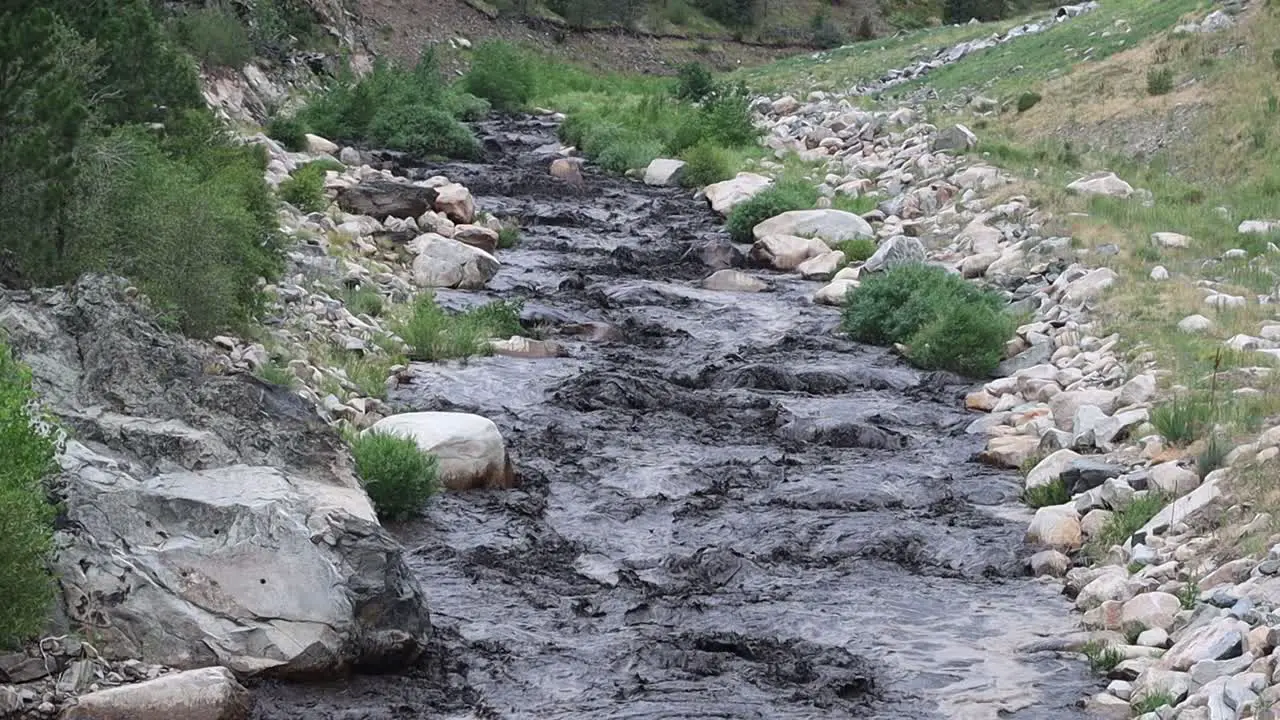 Big Thompson river blackened by ash and mud following a mud slide in a burn scar area near Glen Haven Colorado July 15 2022