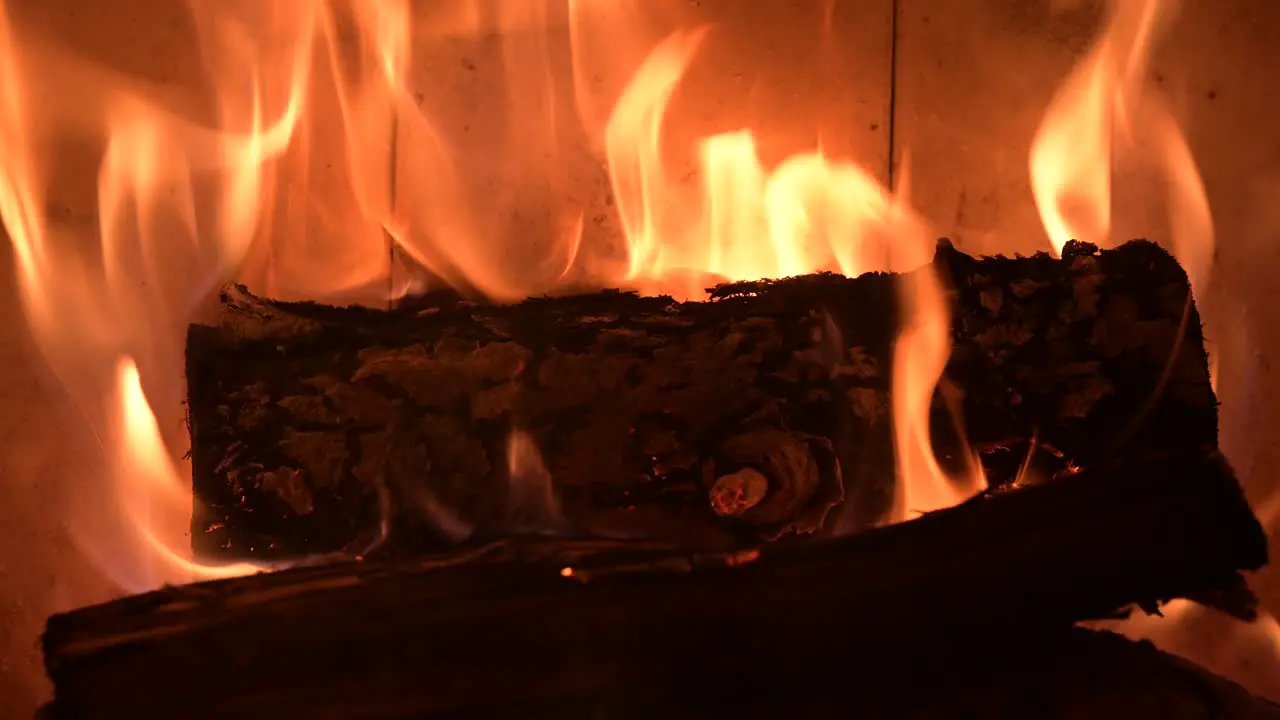 fire flame burning chopped wood piece in fireplace at home extreme close up