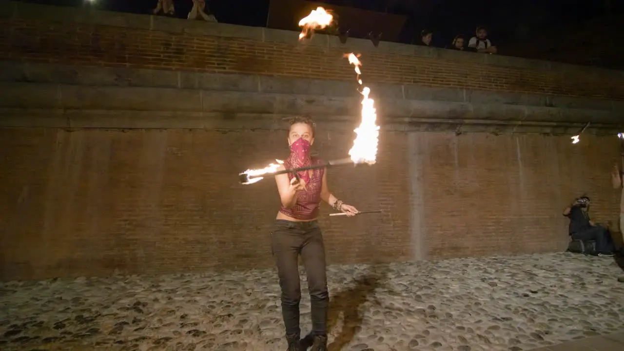 Slow Motion Close up and Panning of Fire sticks spinning by girl wearing bandana over her face