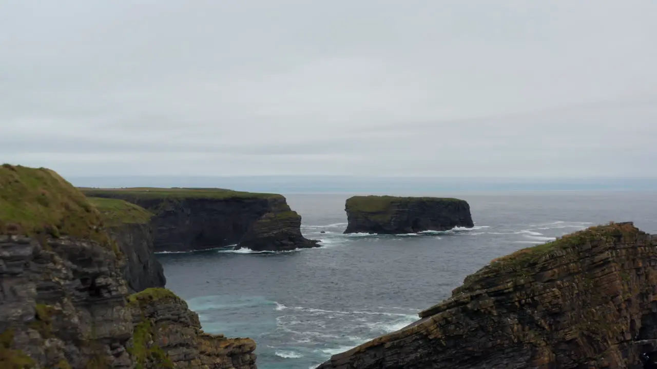 Forwards fly along sea coast High cliffs rocky islands and islets in waves Aerial footage on natural scenery Kilkee Cliff Walk Ireland