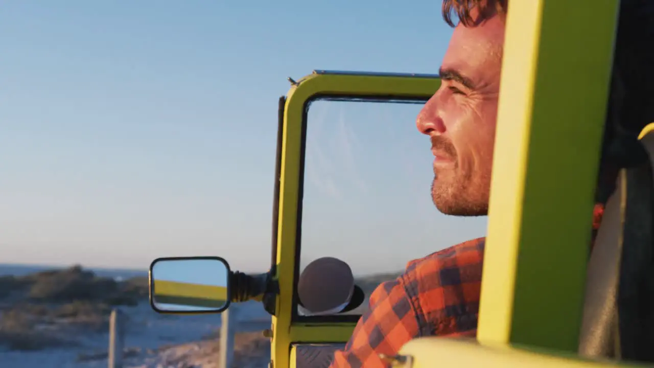 Happy caucasian man sitting in beach buggy by the sea