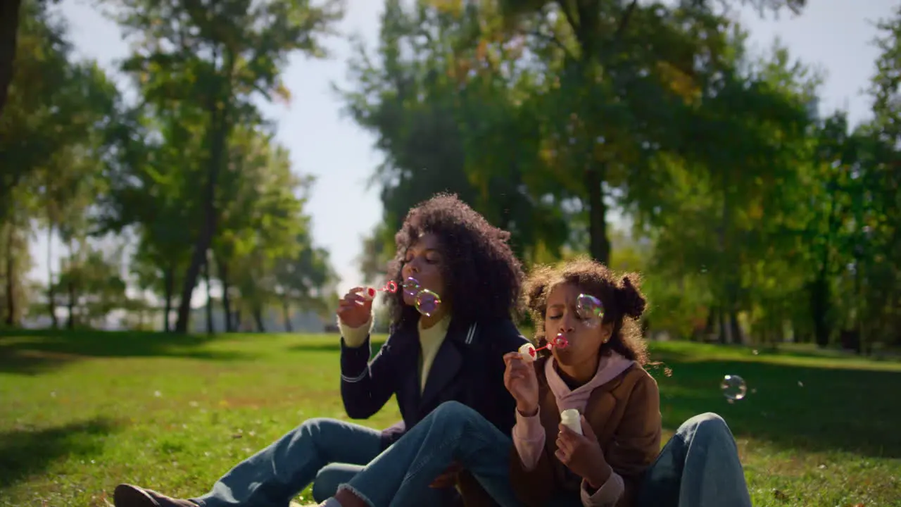 Family blowing air bubbles enjoying warm spring day park Mother day celebration