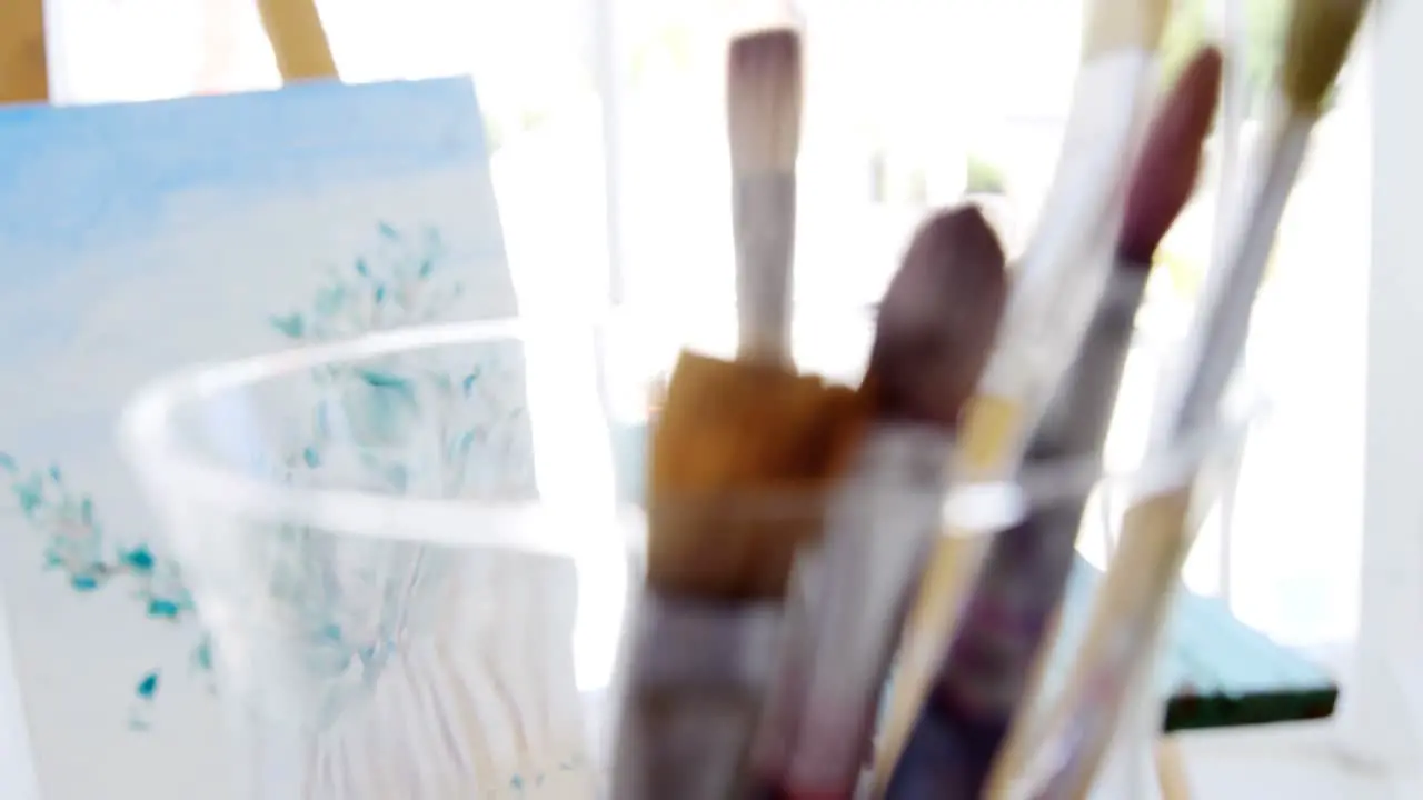 Paintbrushes with painting on easel 