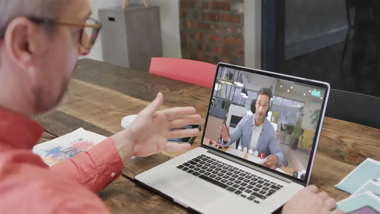 Caucasian businessman on laptop video call with caucasian male colleague on screen