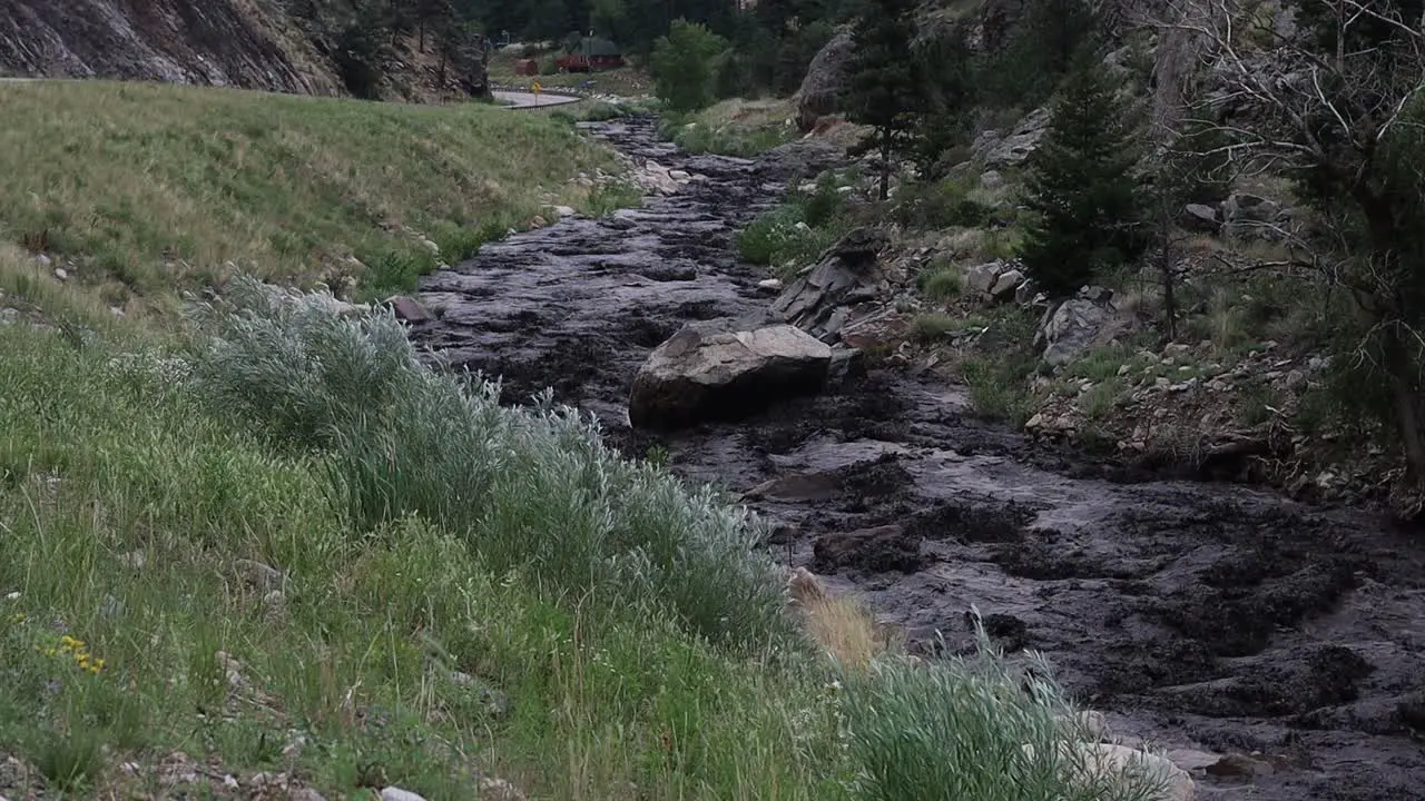 Big Thompson river runs black with mud and ash during a mudslide near Glen Haven Colorado after a sudden summer storm