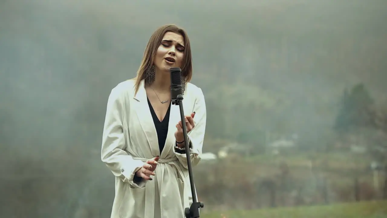 Young artist girl surrounded by fire and smoke singing on microphone