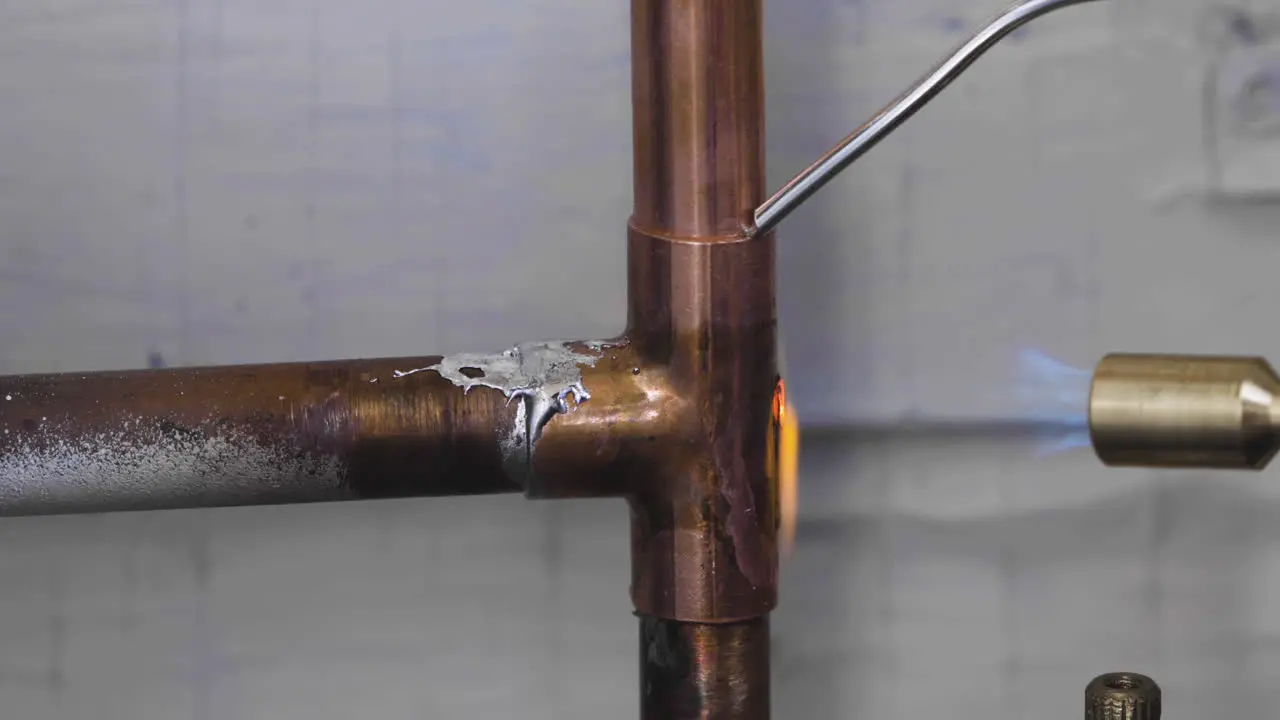 Welding the top and bottom of a copper pipe tee fitting during a burst pipe DIY home repair