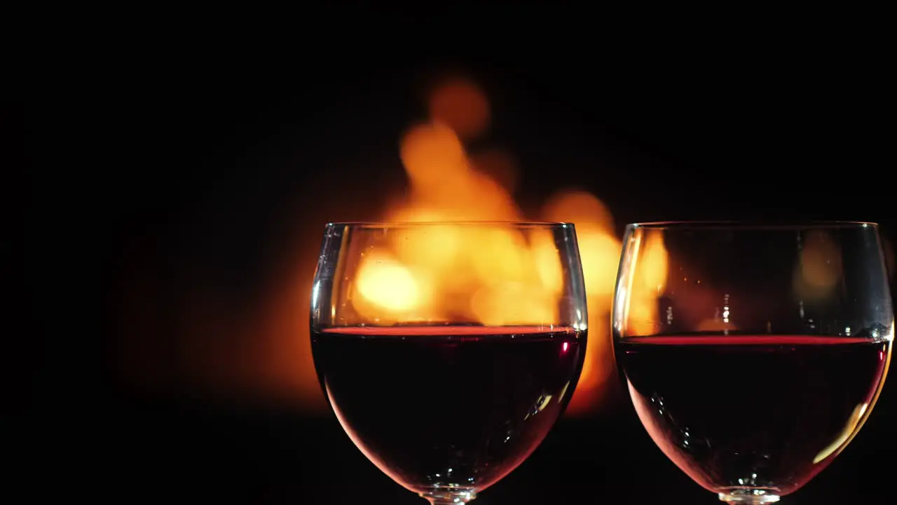 Two Glasses Of Red Wine Against The Background Of The Fireplace Where The Fire Burns