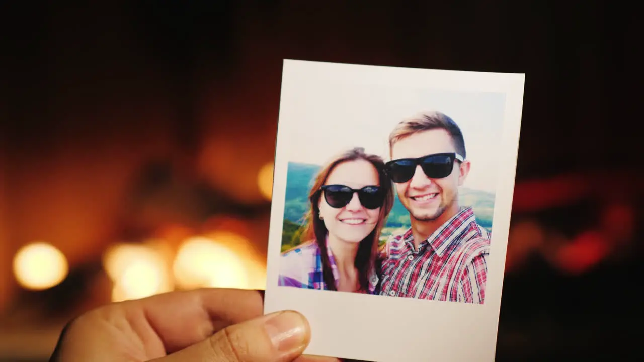 A Hand Holds A Burning Photo Of A Young Couple Then Throws It Into The Fireplace