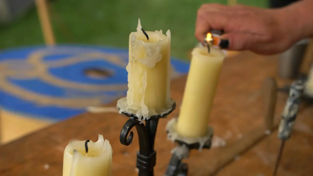 Old used candles with melted wax on rustic black candlestick placed on table hand with black nails lights them