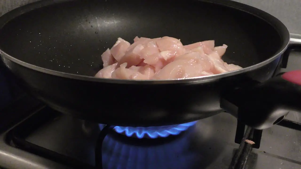 Gas fire burning under pan filled with healthy chicken meat