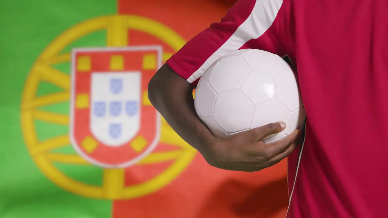 Young Footballer Walking Holding Football In Front of Portugal Flag