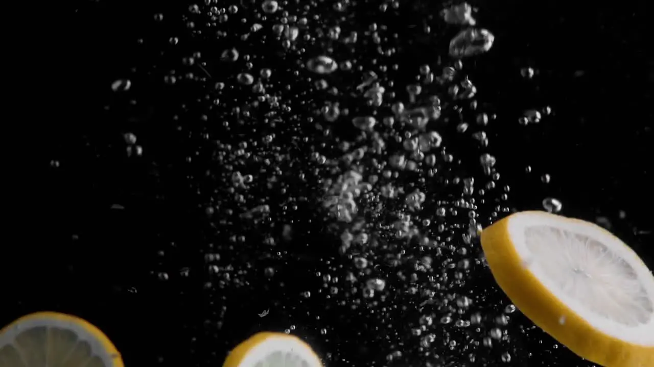 Lemon Slices Falling into Water Super Slowmotion Black Background lots of Air Bubbles 4k240fps