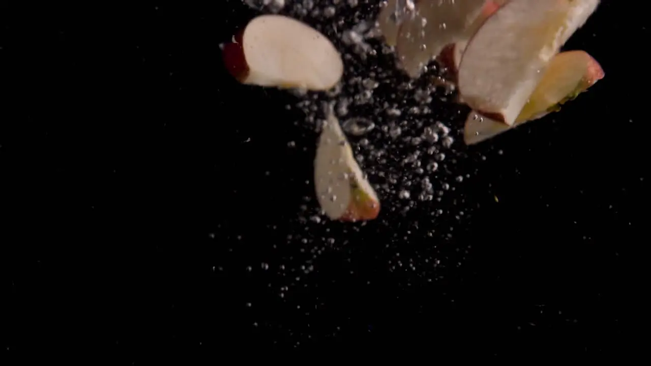 Apple Slices Falling into Water Super Slowmotion Black Background lots of Air Bubbles 4k240fps