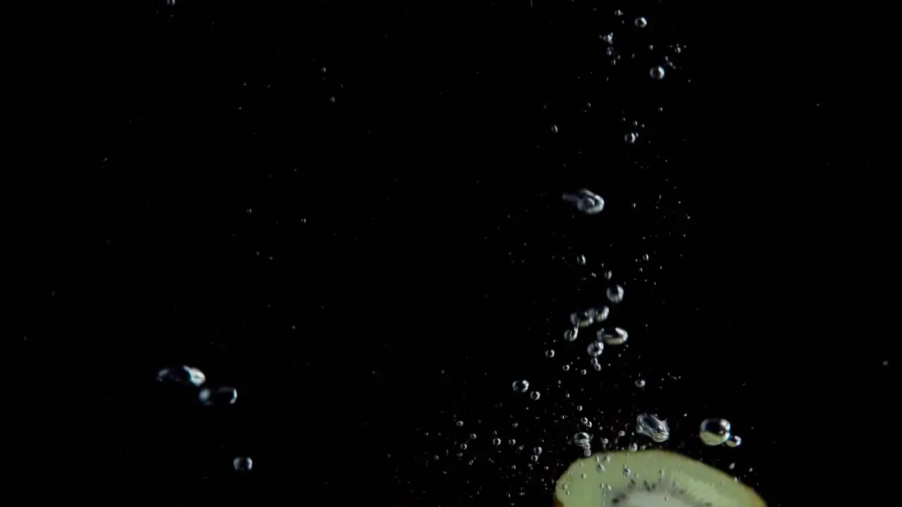 Kiwi Falling into Water Super Slowmotion Black Background lots of Air Bubbles 4k240fps