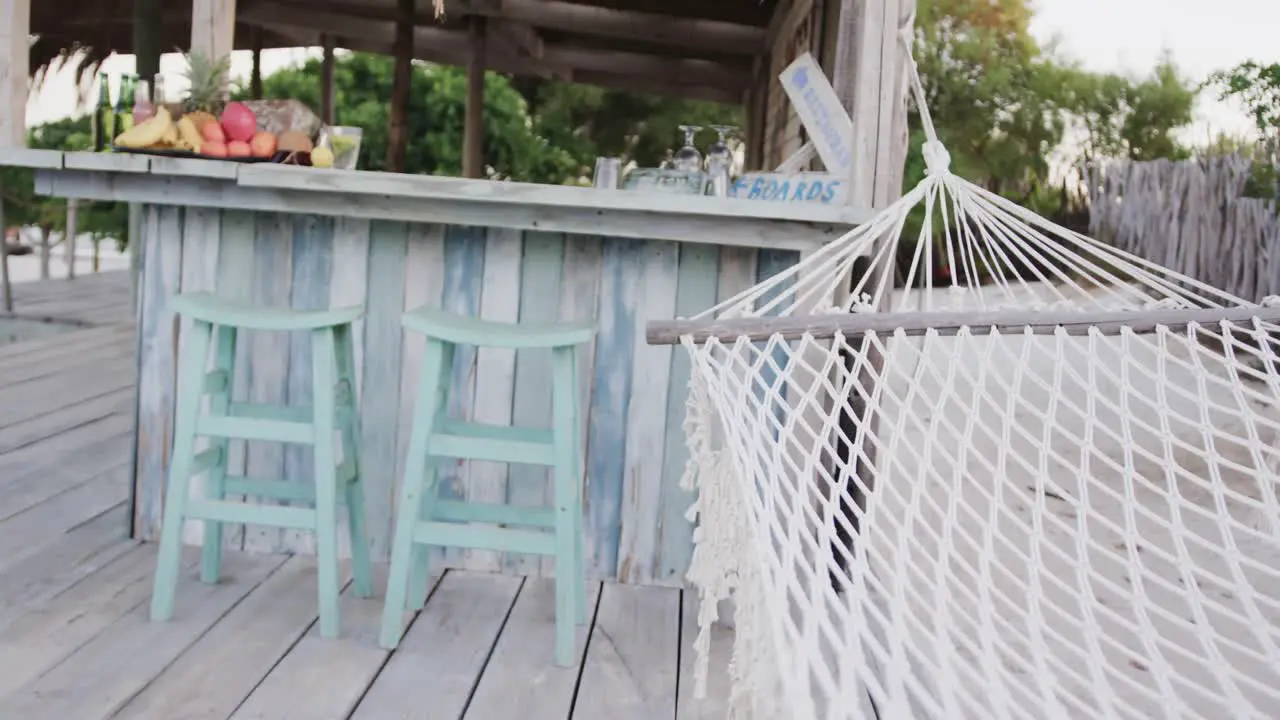 Empty hammock swinging and stools by the counter at beach bar in slow motion