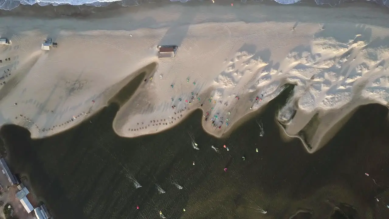 Bird's-eye drone shot of the shore in Combuco Brazil with kiteboarders surfing