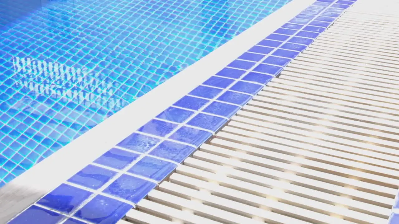 Ceramic blue tiles in swimming pool at relaxing vacation destination with inviting cool crystal clear water close up