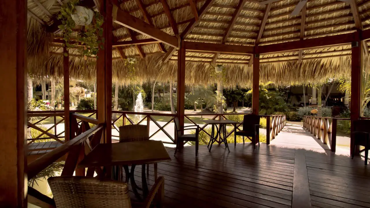 Thatched wooden gazebo with tables and chairs built over pond luxury resort