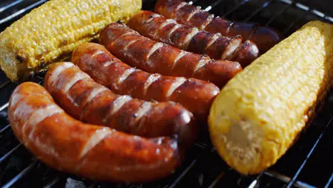 Five delicious sausages grilling with corn