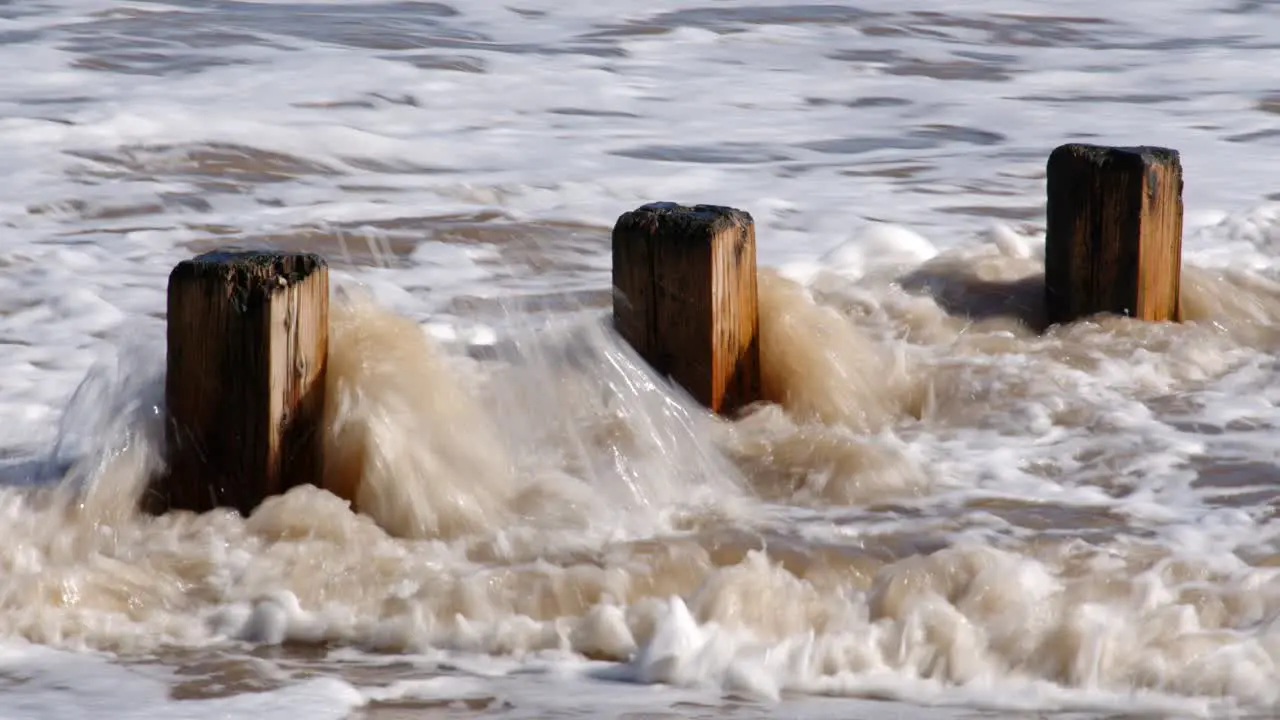 Waves crashing in to groynes on Skegness beach mid shot