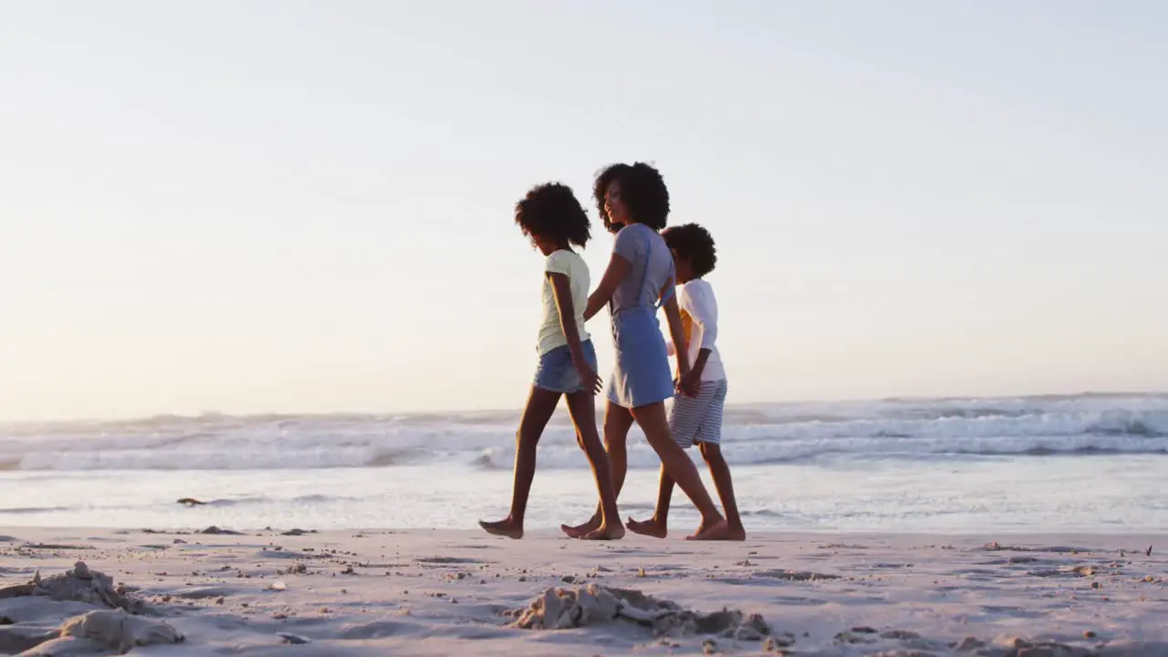 African american mother son and daughter having fun walking together on the beach