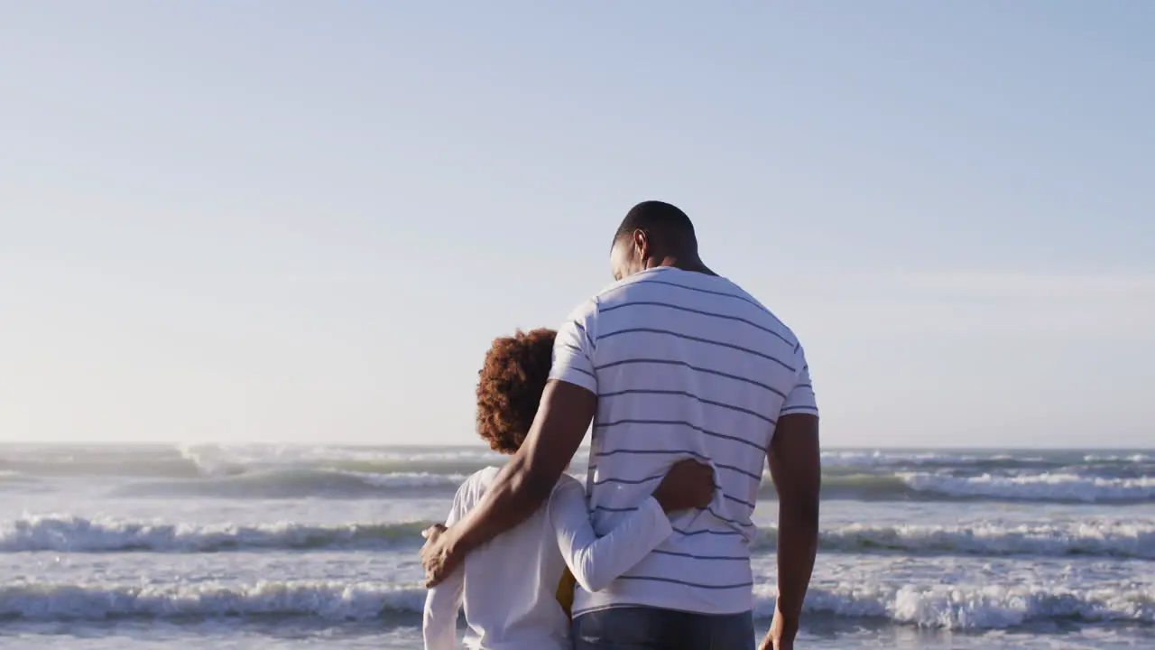 Rear view of african american father and son enjoying the view while standing the beach