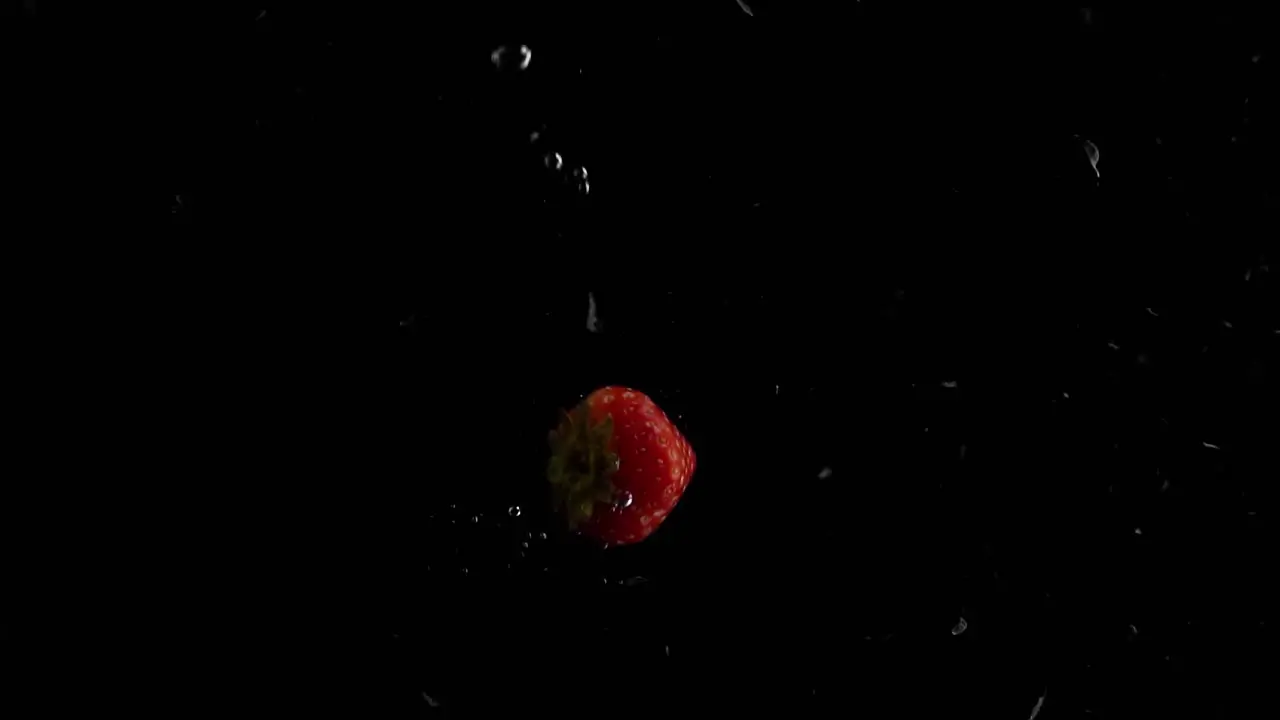 Strawberry Falling into Water Super Slowmotion Black Background lots of Air Bubbles 4k240fps