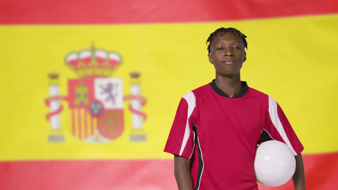 Young Footballer Walking Holding Football In Front of Spain Flag 02