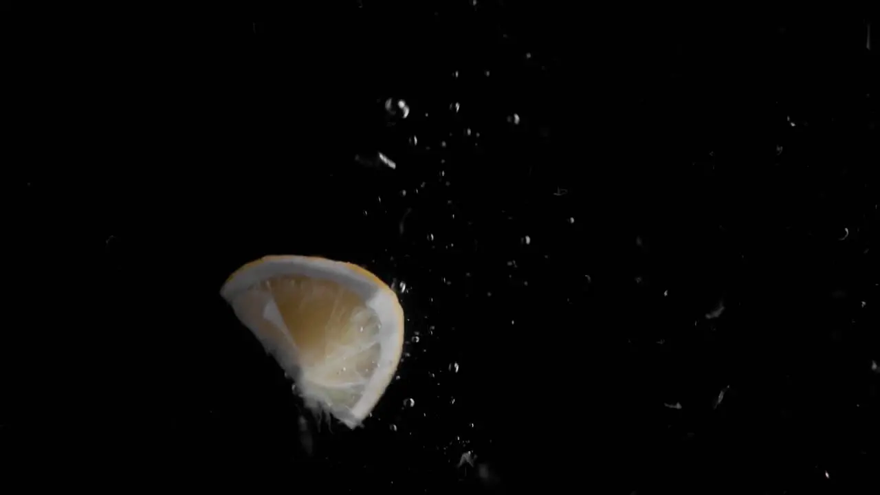 Lemon Piece Falling into Water Super Slowmotion Black Background lots of Air Bubbles 4k240fps