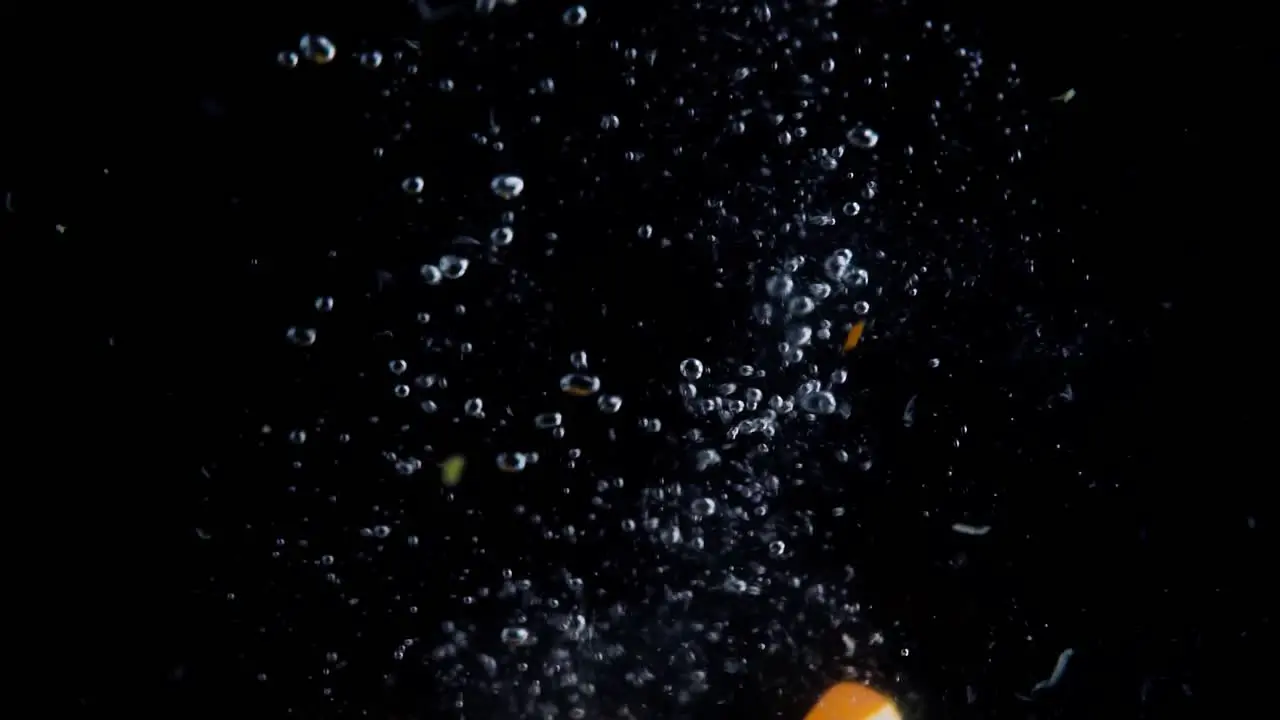 Orange Slices Falling into Water Super Slowmotion Black Background lots of Air Bubbles 4k240fps