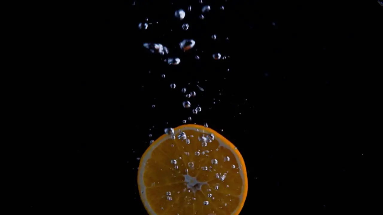 Orange Falling into Water Super Slowmotion Black Background lots of Air Bubbles 4k240fps