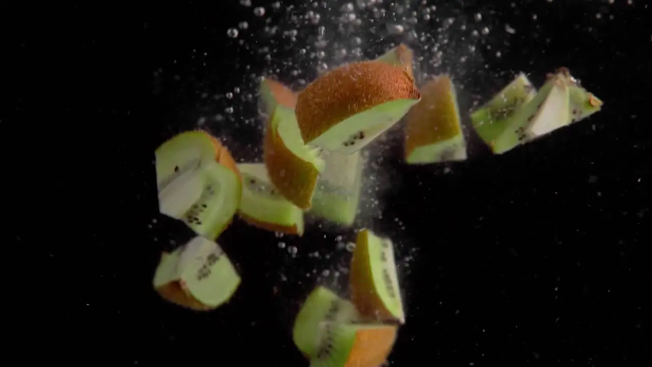 Kiwi Pieces Falling into Water Super Slowmotion Black Background lots of Air Bubbles 4k240fps