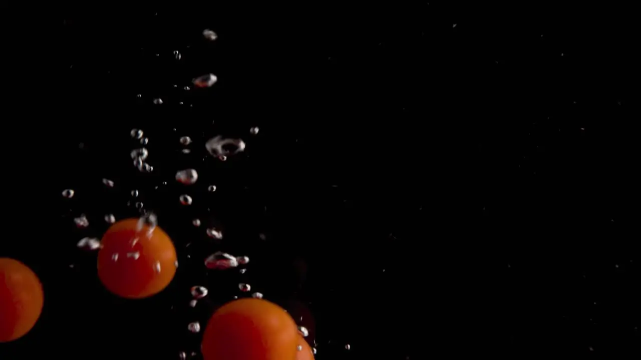 Tomatoes Falling into Water Super Slowmotion Black Background lots of Air Bubbles 4k240fps