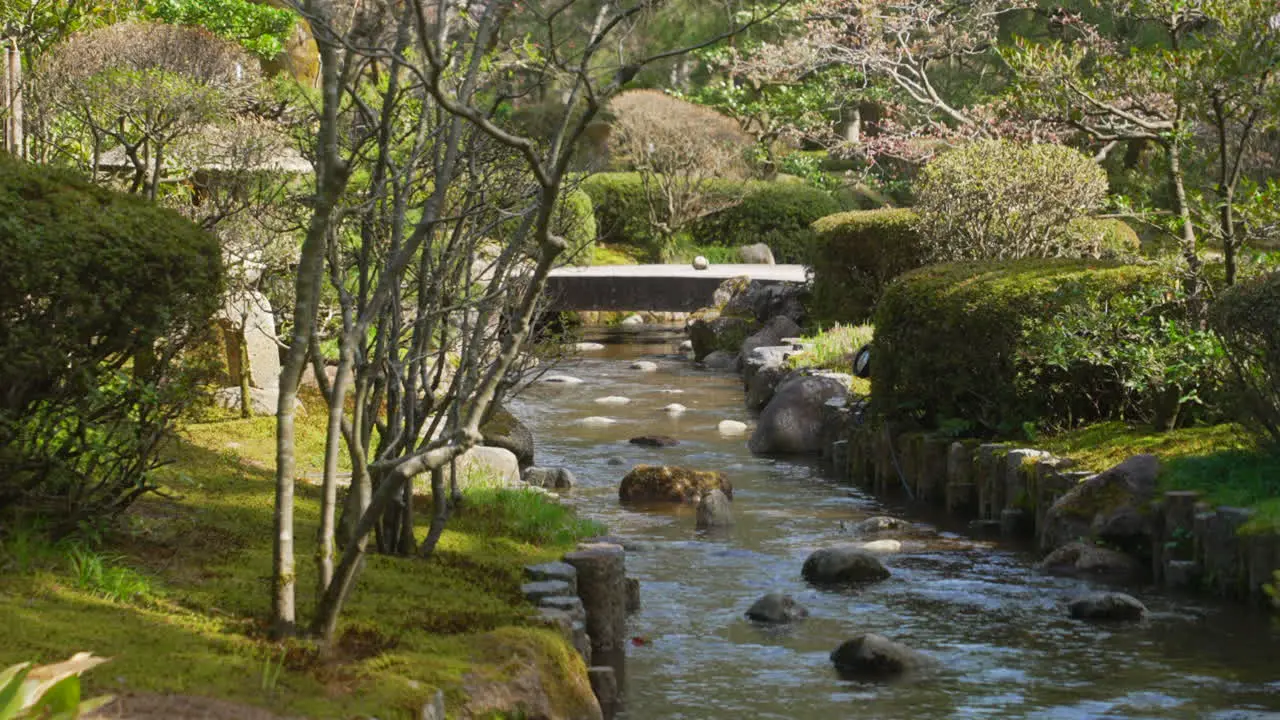 Shot of a soft-flowing stream with stone bridge in the background at Kenrokuen Garden Kanazawa during spring time