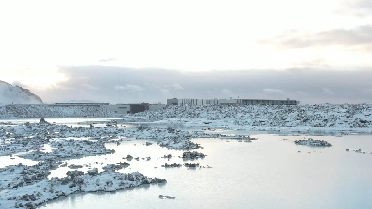 Calm water of Blue Lagoon in Iceland with volcanic rock covered in snow