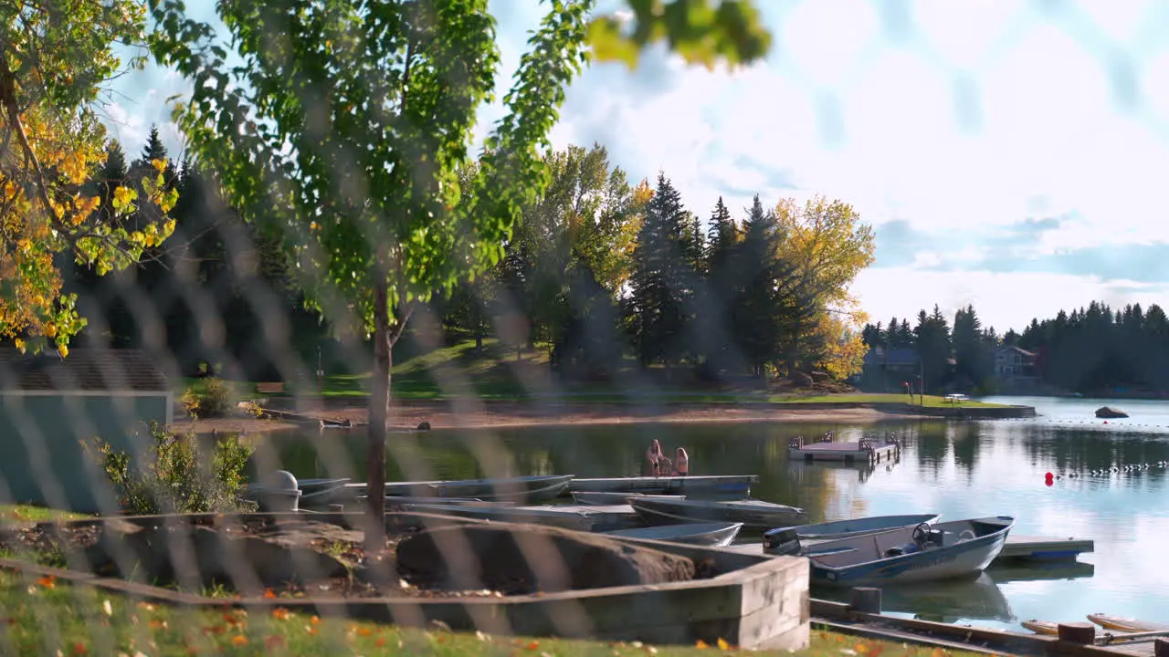 Calm lakeside view on a mild summer day in Canada through a chain link fence looking at a private lake