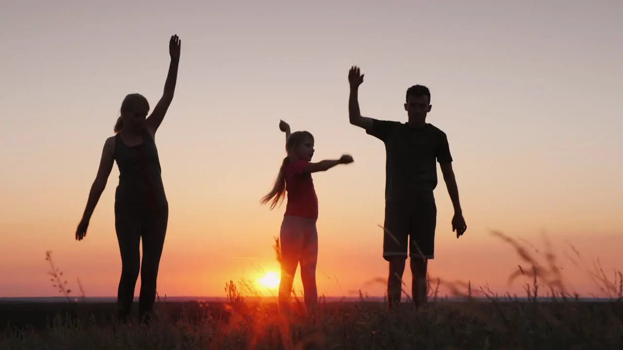 Young Family With A Child Doing Exercises In A Beautiful Place At Sunset