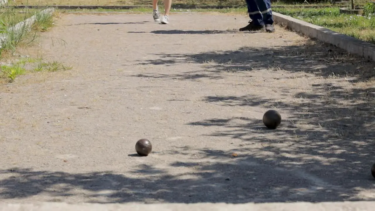 Girl throws bocce ball with man on a field