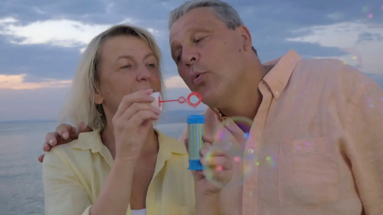 Senior couple blowing bubbles at the seaside